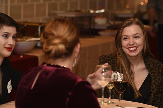 Photo of three Chatham University students clinking wine glasses at an evening networking event. 